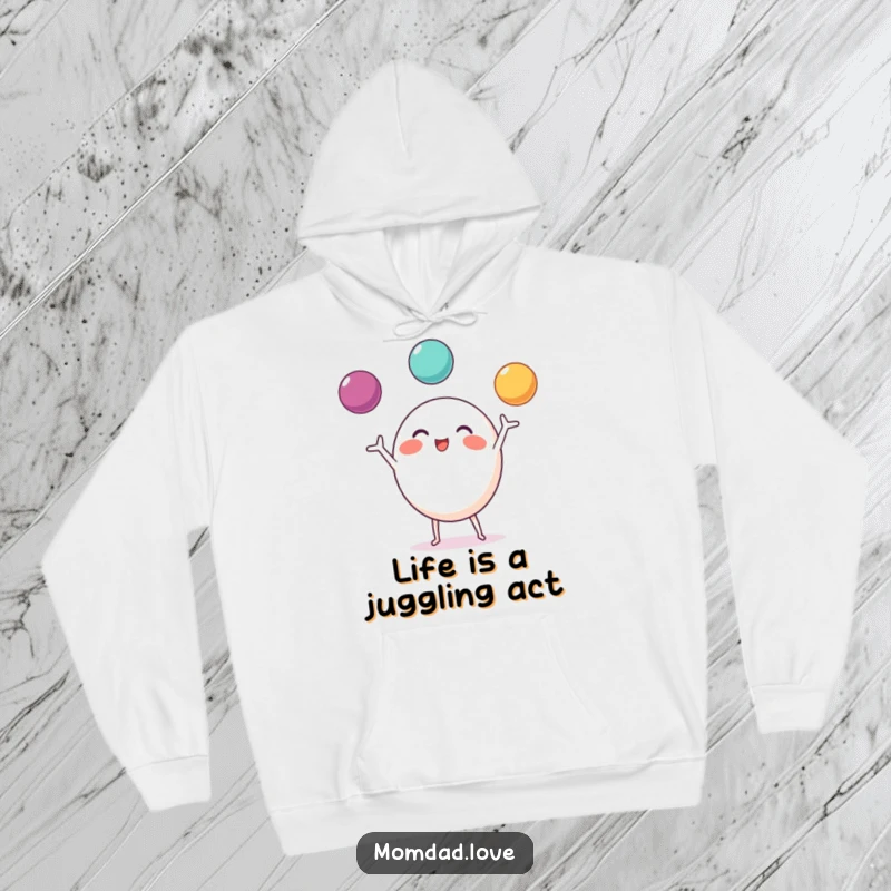 Funny Hoodie showcasing a round character with small limbs, excitedly juggling three colorful balls.